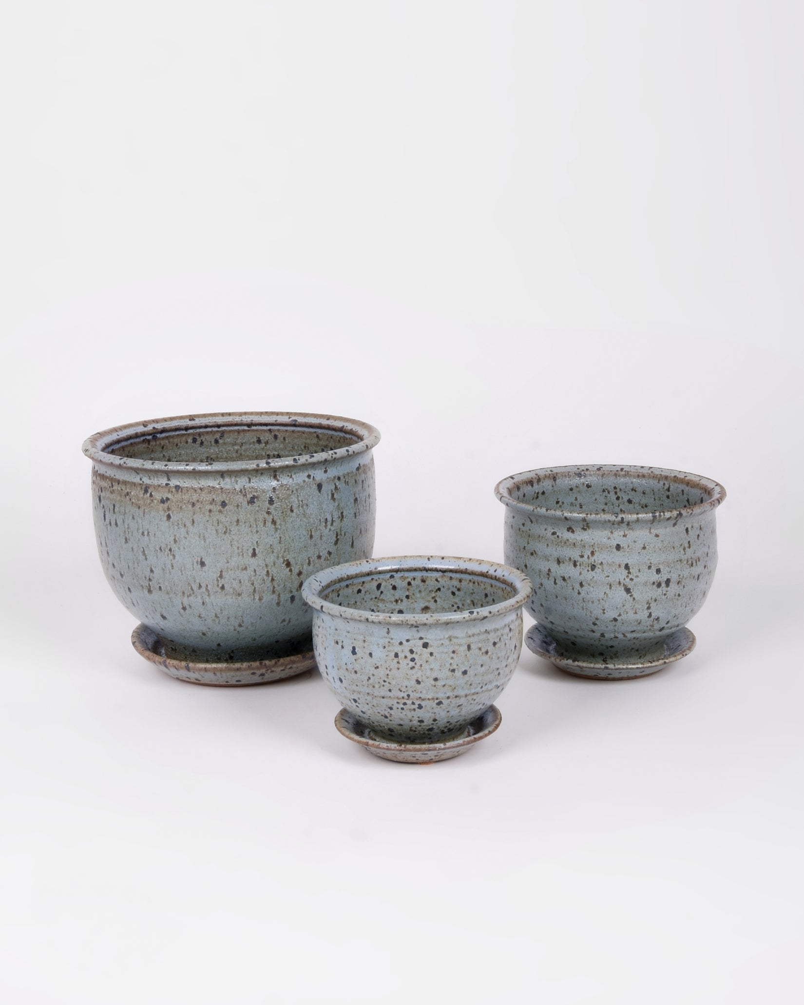 Three powder blue handthrown circular planters with small specks of black and a slightly matte appearance
