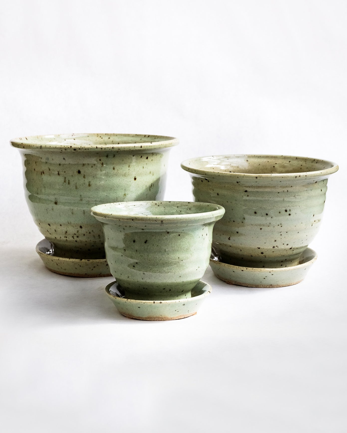 Handcrafted natural green speckled pots with attached drainage tray on white background