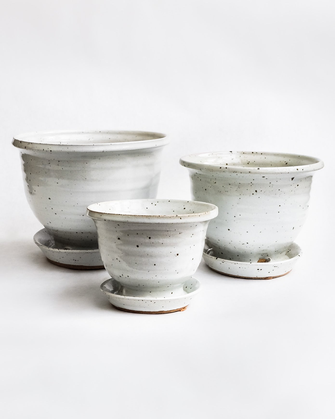Handcrafted white speckled pots with attached drainage tray on white background