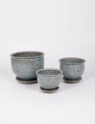 Three powder blue handthrown circular planters with small specks of black and a slightly matte appearance