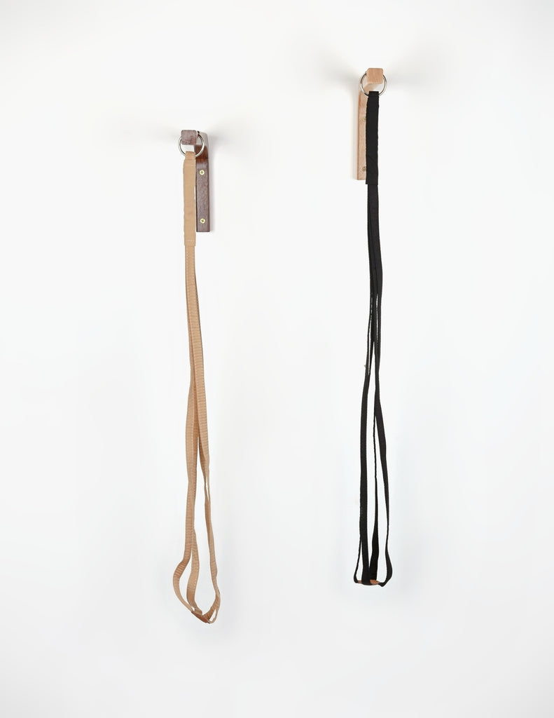 Empty Black and Tan fabric plant hangers hung side by side on white wall