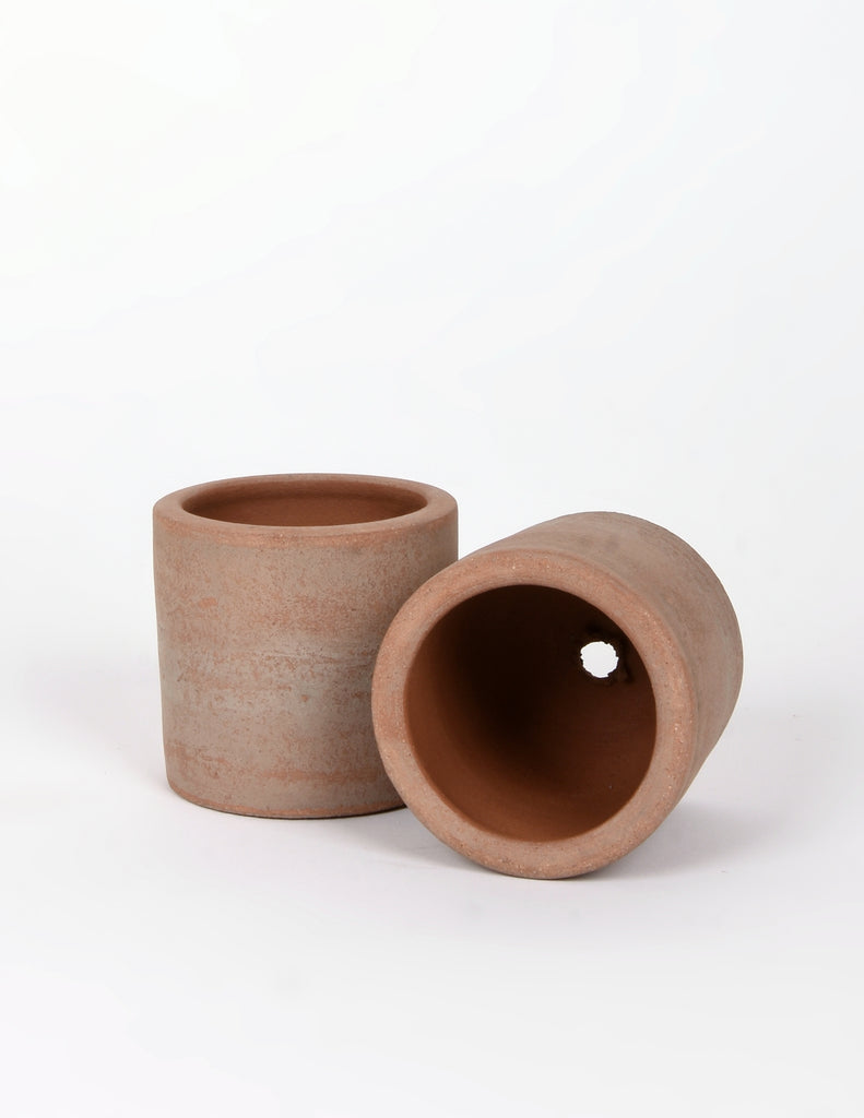 Two empty selene pots, one tipped on its side to show small drainage hole at bottom of pot